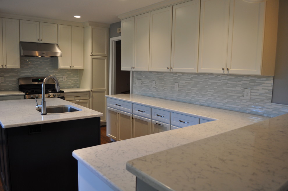 Example of a large transitional u-shaped medium tone wood floor eat-in kitchen design in DC Metro with a single-bowl sink, recessed-panel cabinets, white cabinets, marble countertops, blue backsplash, glass tile backsplash, stainless steel appliances and an island