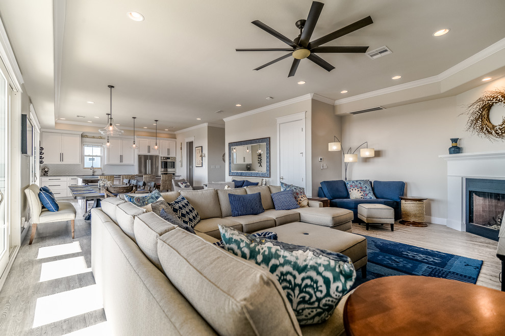 This is an example of a mid-sized beach style living room in Houston with grey walls, ceramic floors, a standard fireplace, a wood fireplace surround and beige floor.