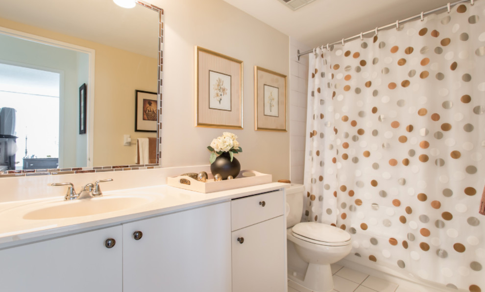 Photo of a mid-sized contemporary master bathroom in Toronto with flat-panel cabinets, white cabinets, an alcove tub, a shower/bathtub combo, a two-piece toilet, beige tile, beige walls, porcelain floors, an integrated sink, laminate benchtops, beige floor, a shower curtain, porcelain tile and beige benchtops.