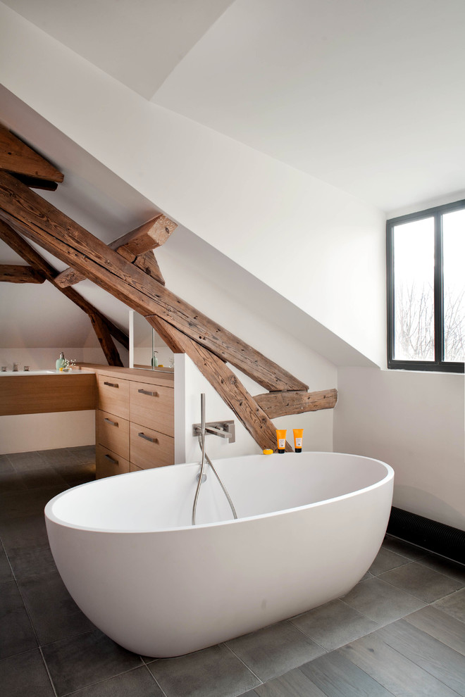 Contemporary bathroom in Paris with flat-panel cabinets, medium wood cabinets, a freestanding tub and white walls.