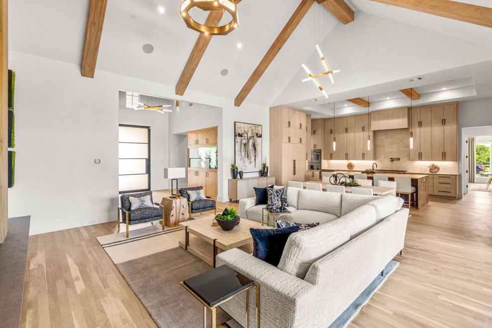 This is an example of a large modern open concept living room in Dallas with multi-coloured walls, light hardwood floors, a ribbon fireplace, a stone fireplace surround and exposed beam.