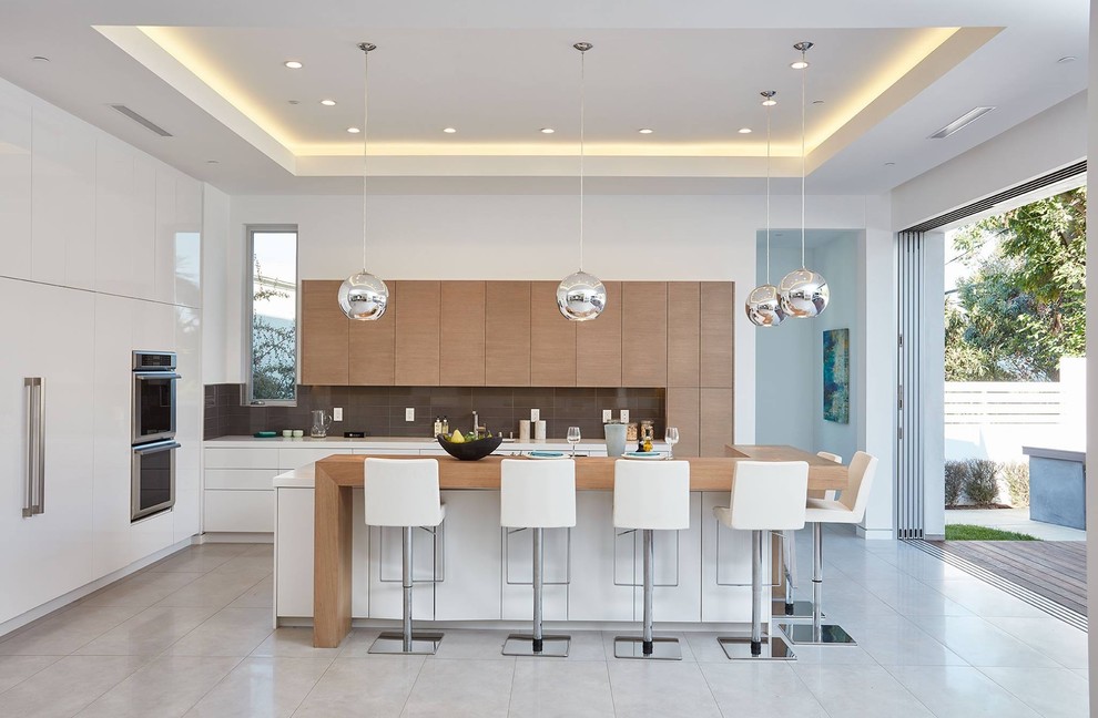 This is an example of a large contemporary u-shaped eat-in kitchen in Orange County with an undermount sink, flat-panel cabinets, white cabinets, quartz benchtops, beige splashback, porcelain splashback, panelled appliances, concrete floors, with island, grey floor and white benchtop.