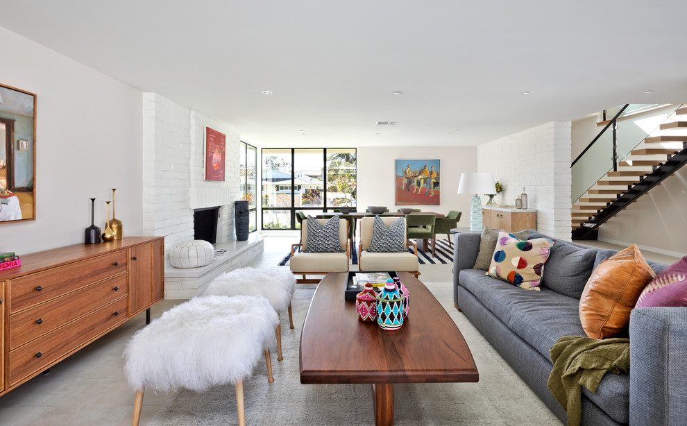 Midcentury open concept living room in Orange County with white walls, concrete floors, a standard fireplace, a brick fireplace surround, a built-in media wall and grey floor.