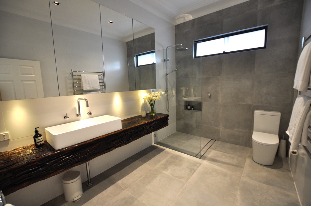 Design ideas for a mid-sized contemporary bathroom in Sydney with flat-panel cabinets, dark wood cabinets, a freestanding tub, an open shower, a one-piece toilet, gray tile, ceramic tile, white walls, ceramic floors, wood benchtops, grey floor and an open shower.