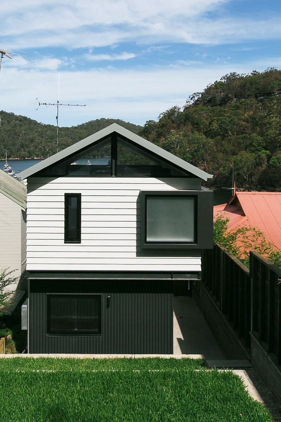 Photo of a small contemporary three-storey white house exterior in Sydney with concrete fiberboard siding, a shed roof and a metal roof.