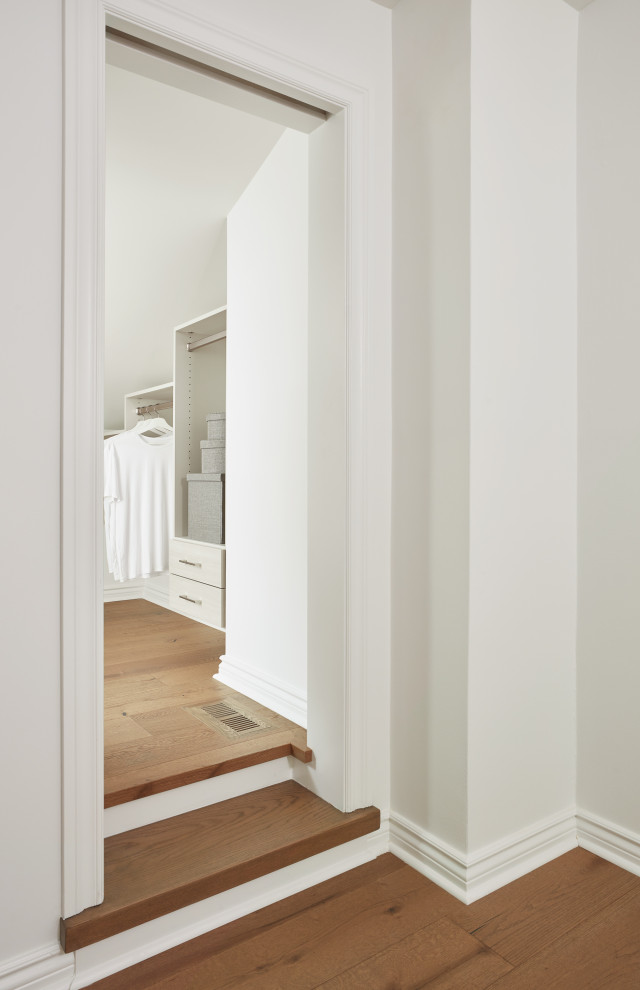 Inspiration for a small gender neutral walk-in wardrobe in Toronto with flat-panel cabinets, grey cabinets, medium hardwood flooring, brown floors and a vaulted ceiling.