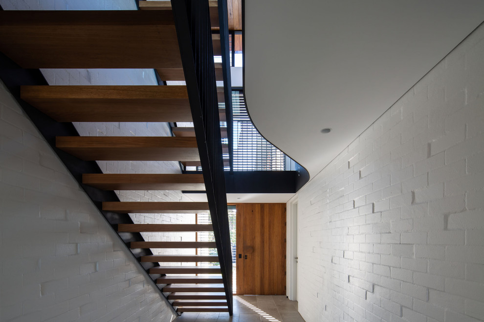 Example of a trendy wooden straight open, metal railing and brick wall staircase design in Sydney