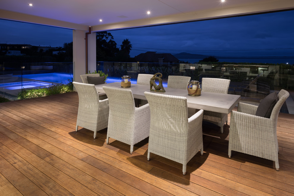 Photo of a large contemporary backyard deck in Auckland with a roof extension.