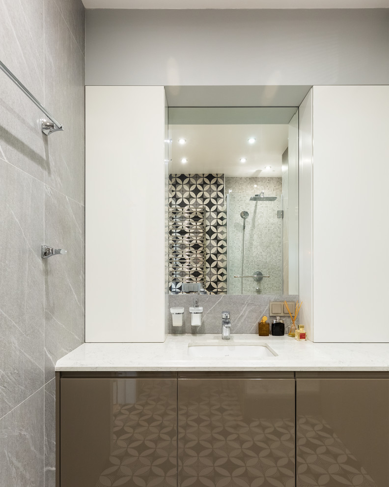 This is an example of a mid-sized contemporary 3/4 bathroom in Moscow with flat-panel cabinets, beige cabinets, a corner shower, a wall-mount toilet, black and white tile, ceramic tile, beige walls, ceramic floors, an undermount sink, solid surface benchtops, black floor, a hinged shower door and white benchtops.