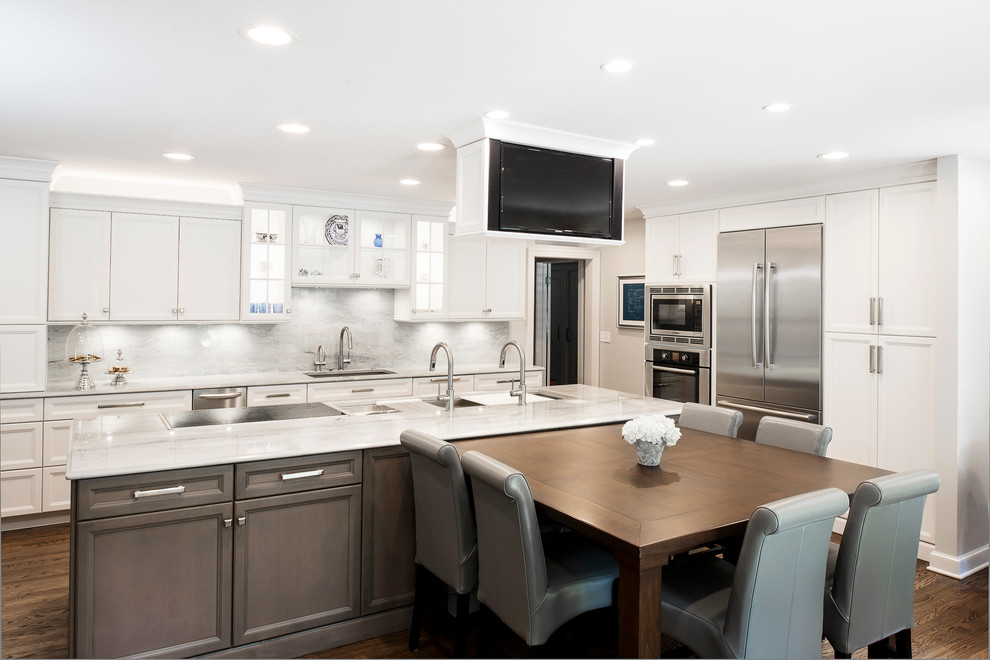 Large transitional single-wall medium tone wood floor and brown floor kitchen photo in Denver with an undermount sink, recessed-panel cabinets, white cabinets, white backsplash, stone slab backsplash, stainless steel appliances and an island