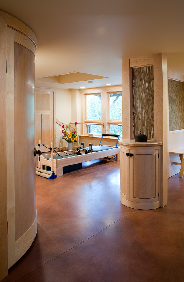 This is an example of a mid-sized transitional home yoga studio in Other with beige walls, concrete floors and brown floor.