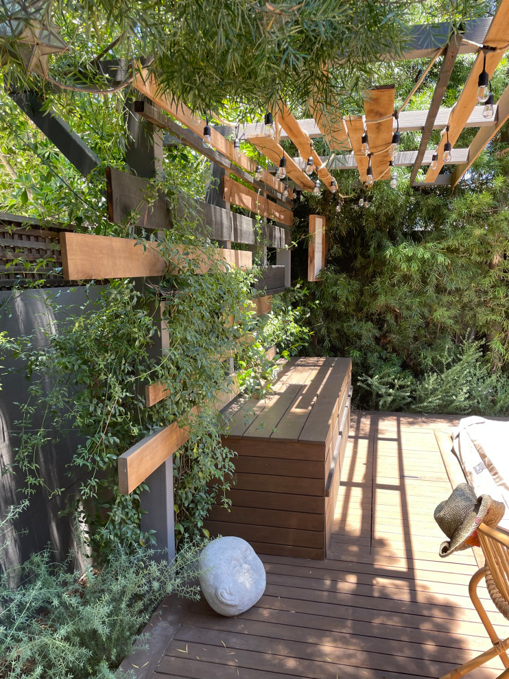 Стильный дизайн: солнечный, весенний засухоустойчивый сад среднего размера на заднем дворе в стиле фьюжн с перегородкой для приватности, хорошей освещенностью, настилом и с деревянным забором - последний тренд