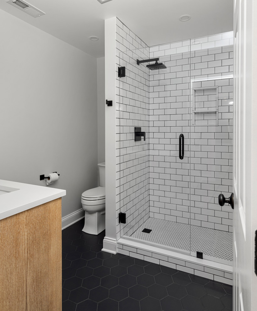 This is an example of a medium sized farmhouse bathroom in Other with grey walls, shaker cabinets, light wood cabinets, all types of shower, grey tiles, metro tiles, porcelain flooring, engineered stone worktops, black floors, a hinged door, white worktops, a wall niche, a single sink and a freestanding vanity unit.