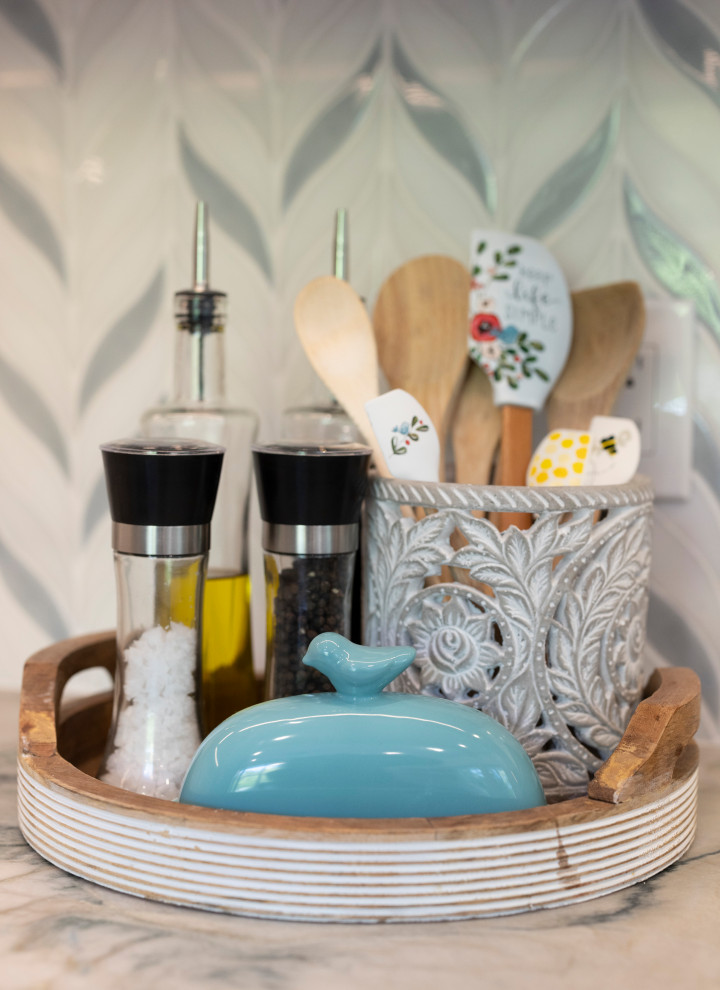 Maritim inredning av ett mellanstort kök och matrum, med en enkel diskho, skåp i shakerstil, skåp i mellenmörkt trä, bänkskiva i kvartsit, blått stänkskydd, stänkskydd i mosaik, svarta vitvaror och skiffergolv