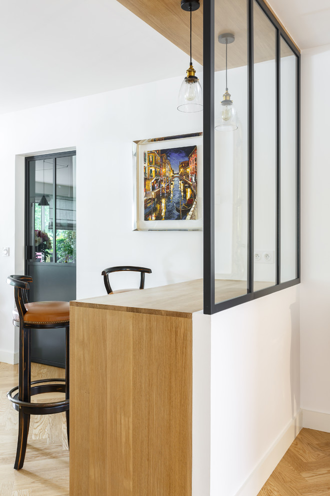 Idée de décoration pour bar de salon in bois clair With des tabourets, aucun évier ou lavabo, un placard à porte vitrée, un plan de travail en bois, parquet clair, un sol beige and un plan de travail beige.
