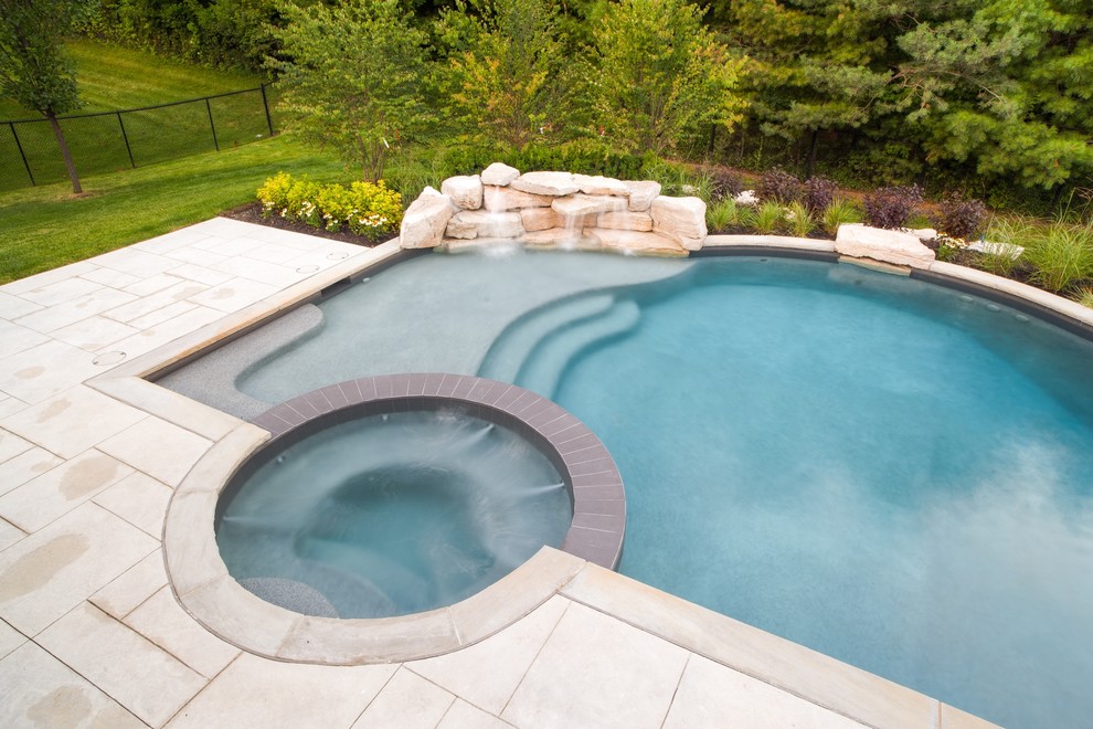 This is an example of a large contemporary backyard custom-shaped natural pool in Toronto with a hot tub and stamped concrete.