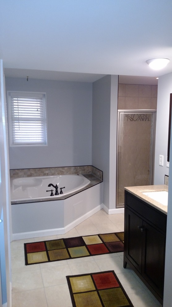 Inspiration for a mid-sized transitional master porcelain tile and beige floor corner bathtub remodel with shaker cabinets, black cabinets, a two-piece toilet, gray walls, an undermount sink, laminate countertops, a hinged shower door and beige countertops