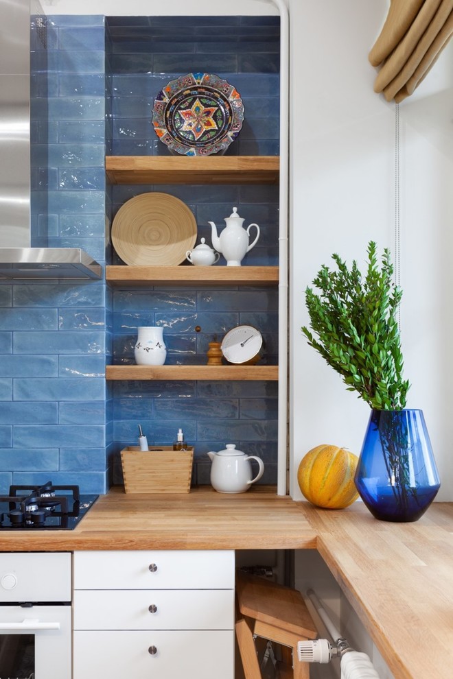 This is an example of a mid-sized asian l-shaped eat-in kitchen in Moscow with a single-bowl sink, flat-panel cabinets, white cabinets, wood benchtops, blue splashback, ceramic splashback, white appliances, ceramic floors, no island, multi-coloured floor and brown benchtop.
