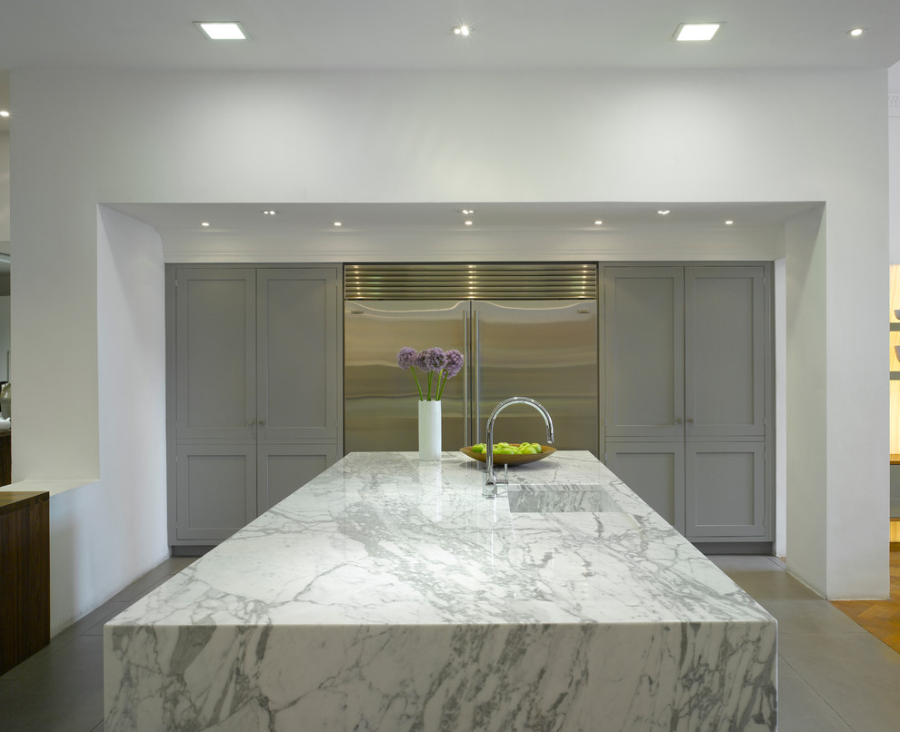 This is an example of a large contemporary open plan kitchen in London with flat-panel cabinets, grey cabinets, marble benchtops, stainless steel appliances and with island.