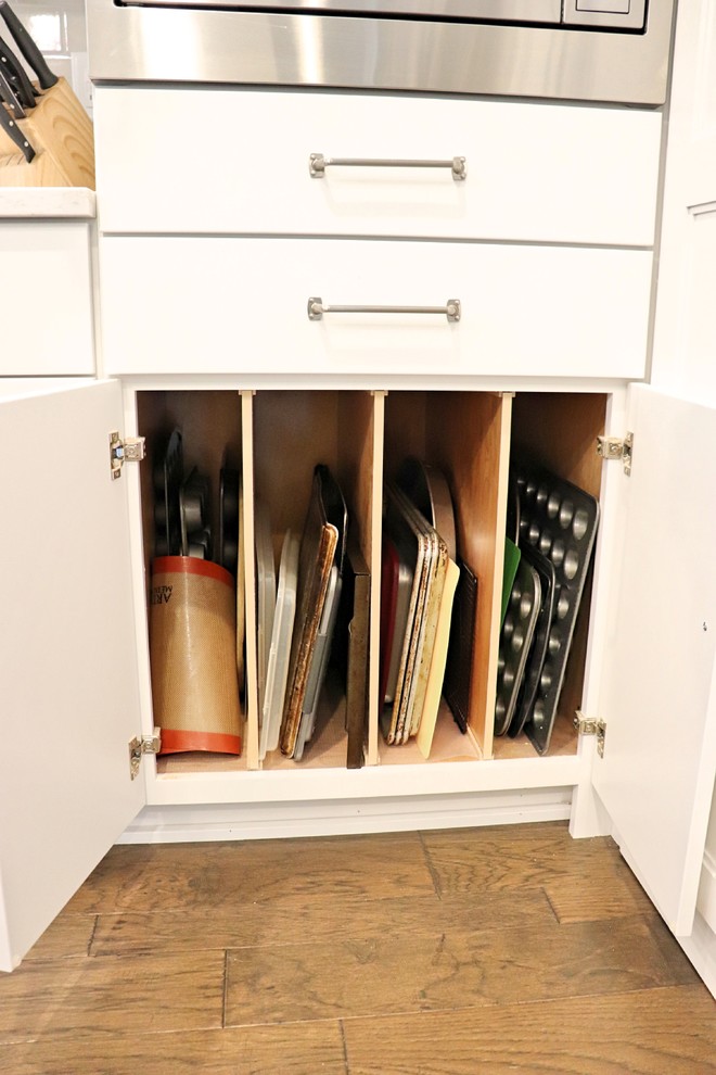 Transitional l-shaped medium tone wood floor and brown floor kitchen pantry photo in Cedar Rapids with an undermount sink, recessed-panel cabinets, white cabinets, quartzite countertops, gray backsplash, porcelain backsplash, stainless steel appliances, an island and white countertops