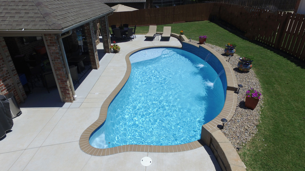 Inspiration for a mid-sized transitional backyard custom-shaped lap pool in Oklahoma City with a water feature and brick pavers.