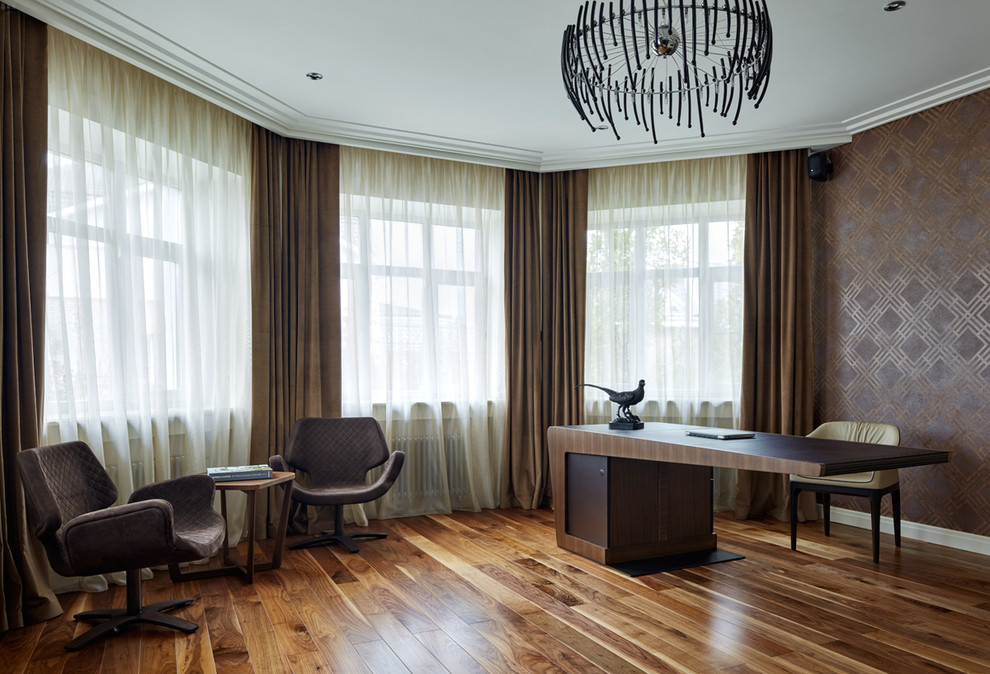 This is an example of a large contemporary study room in Milan with medium hardwood floors, no fireplace, a freestanding desk and brown walls.