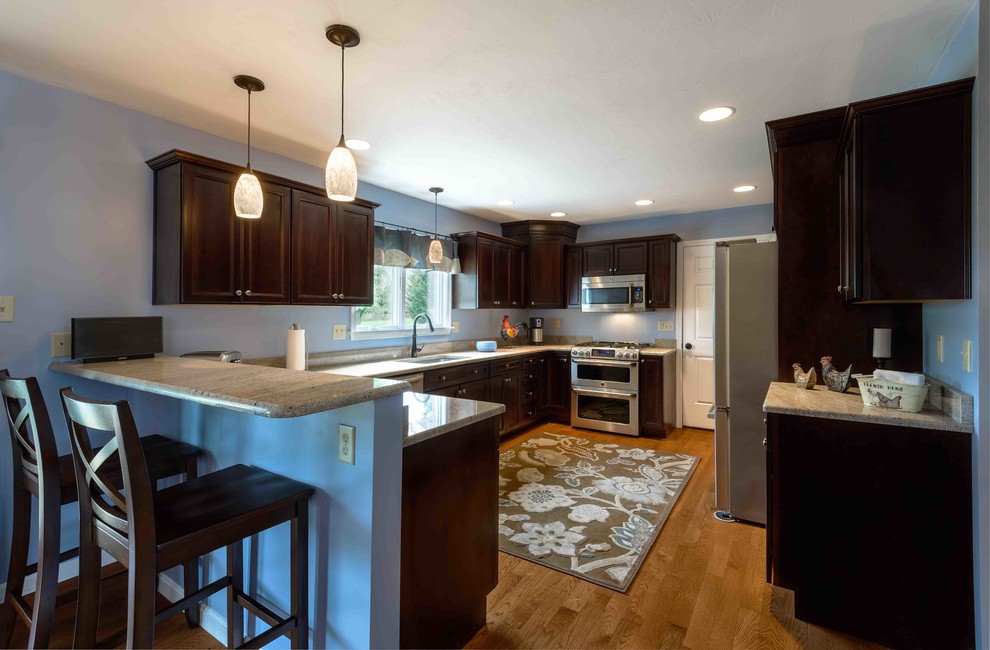 Mid-sized transitional u-shaped medium tone wood floor and brown floor enclosed kitchen photo with an undermount sink, beaded inset cabinets, dark wood cabinets, granite countertops, stainless steel appliances and an island