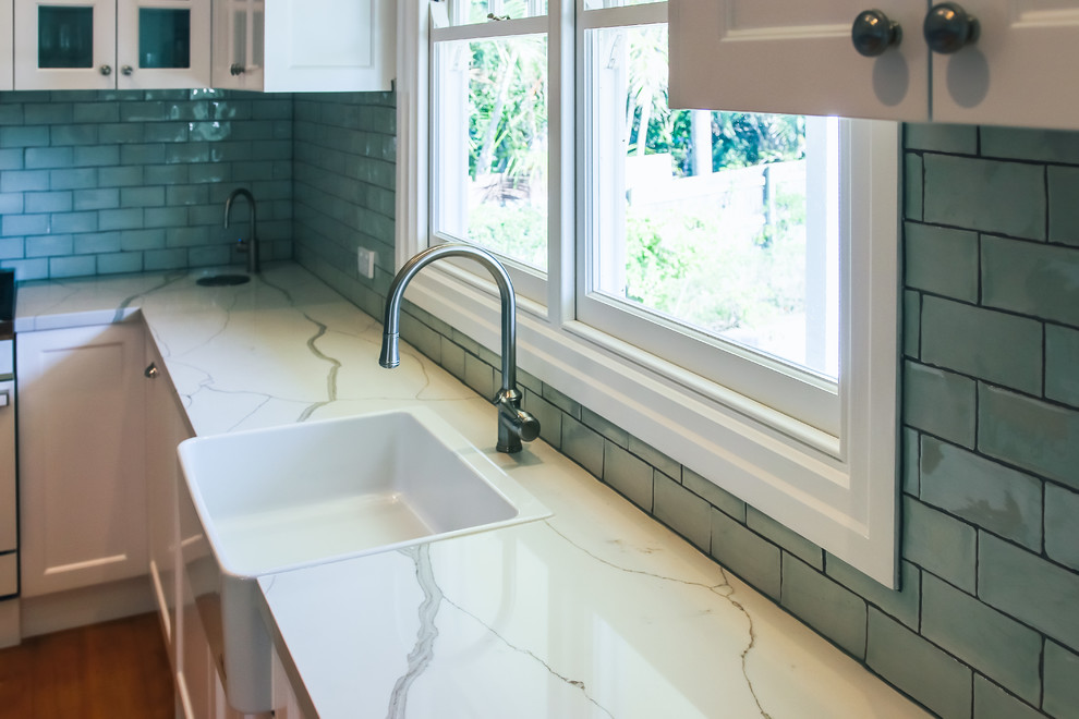 Large traditional l-shaped eat-in kitchen in Brisbane with a farmhouse sink, shaker cabinets, green cabinets, quartz benchtops, green splashback, subway tile splashback, white appliances, medium hardwood floors, with island and green benchtop.