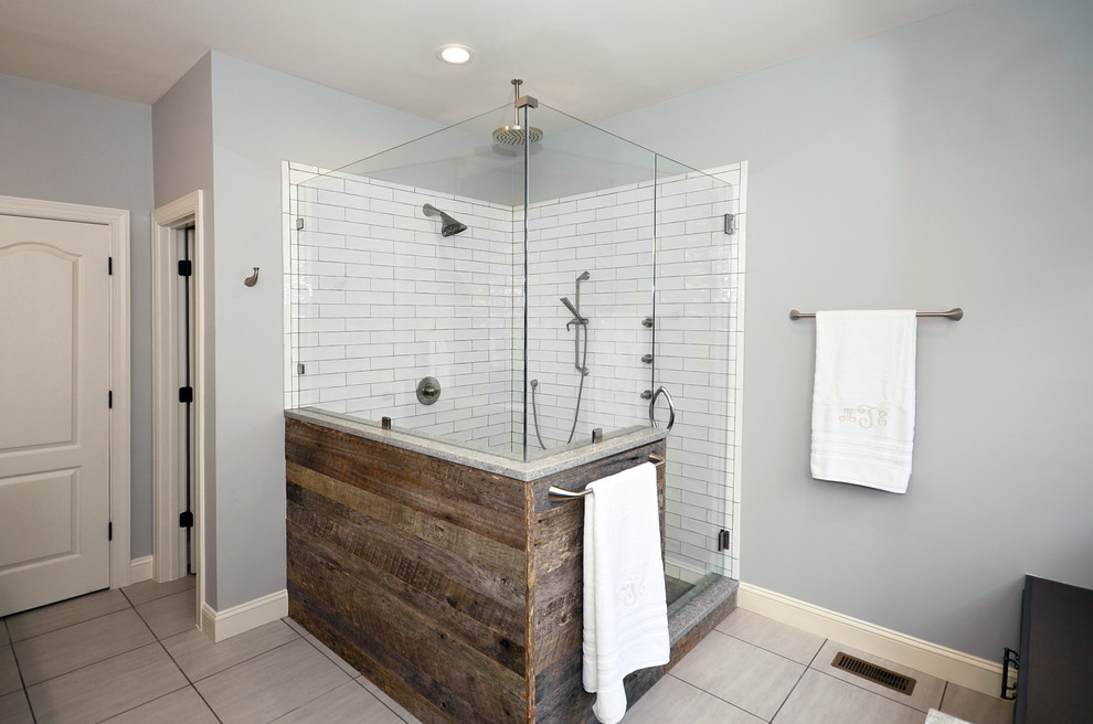 This is an example of a mid-sized country master bathroom in Charlotte with shaker cabinets, brown cabinets, a corner shower, white tile, subway tile, blue walls, porcelain floors, an undermount sink, engineered quartz benchtops, grey floor, a hinged shower door and grey benchtops.