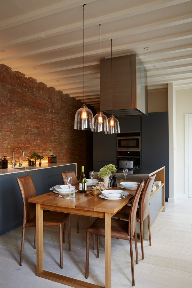 Photo of a mid-sized contemporary eat-in kitchen in London with stainless steel appliances, light hardwood floors, with island and exposed beam.