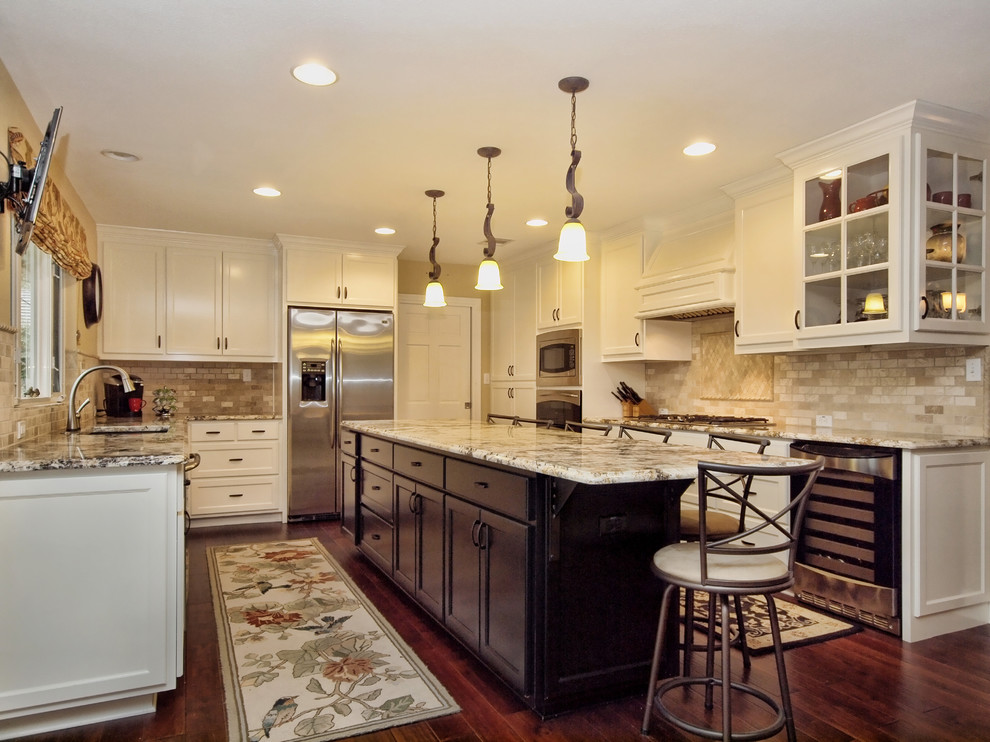 This is an example of a large traditional u-shaped open plan kitchen in Austin with an undermount sink, shaker cabinets, white cabinets, granite benchtops, beige splashback, ceramic splashback, stainless steel appliances, dark hardwood floors, with island and brown floor.