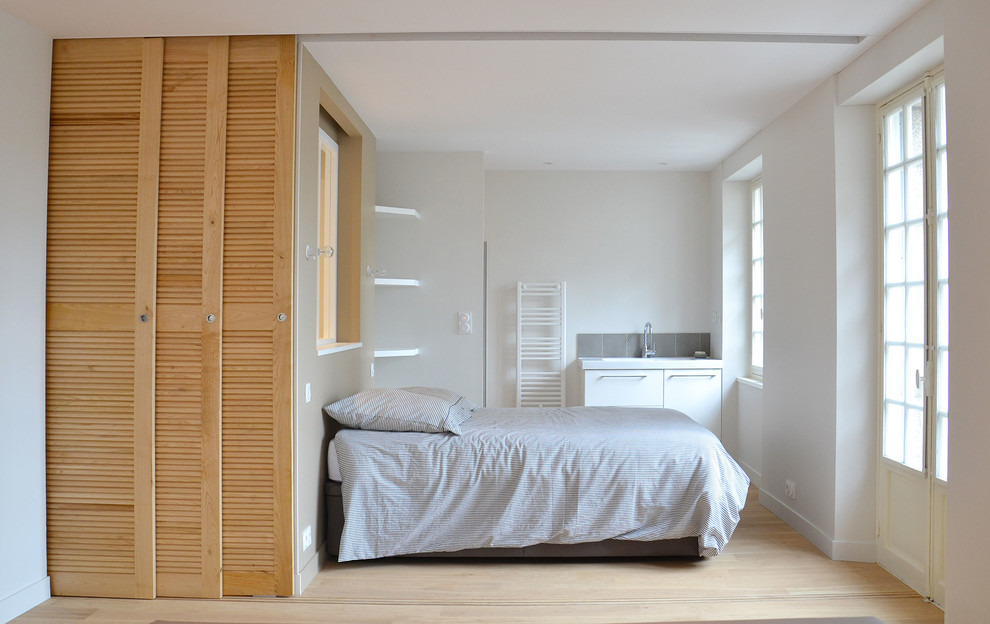 Inspiration for a mid-sized contemporary master bedroom in Rennes with white walls, light hardwood floors and no fireplace.