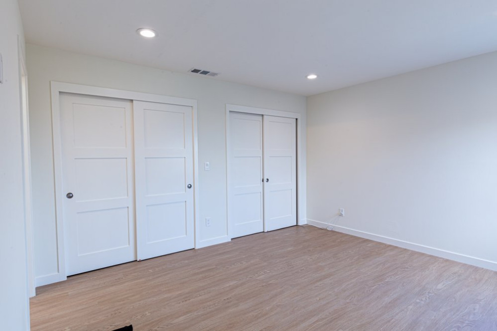 Exemple d'une chambre parentale moderne avec un mur blanc, parquet clair et un sol marron.