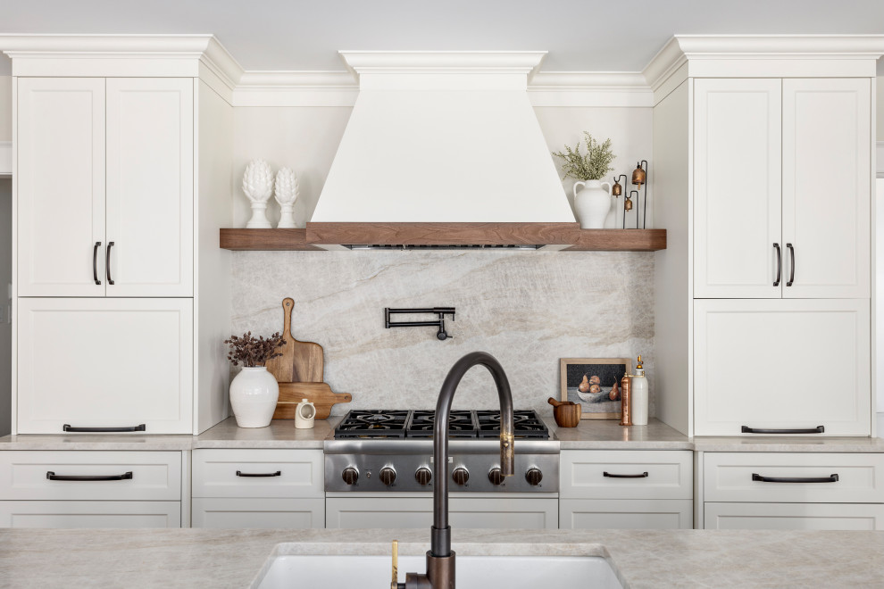 Large transitional l-shaped medium tone wood floor and brown floor open concept kitchen photo with an undermount sink, shaker cabinets, quartz countertops, multicolored backsplash, quartz backsplash, stainless steel appliances, an island, beige countertops and white cabinets
