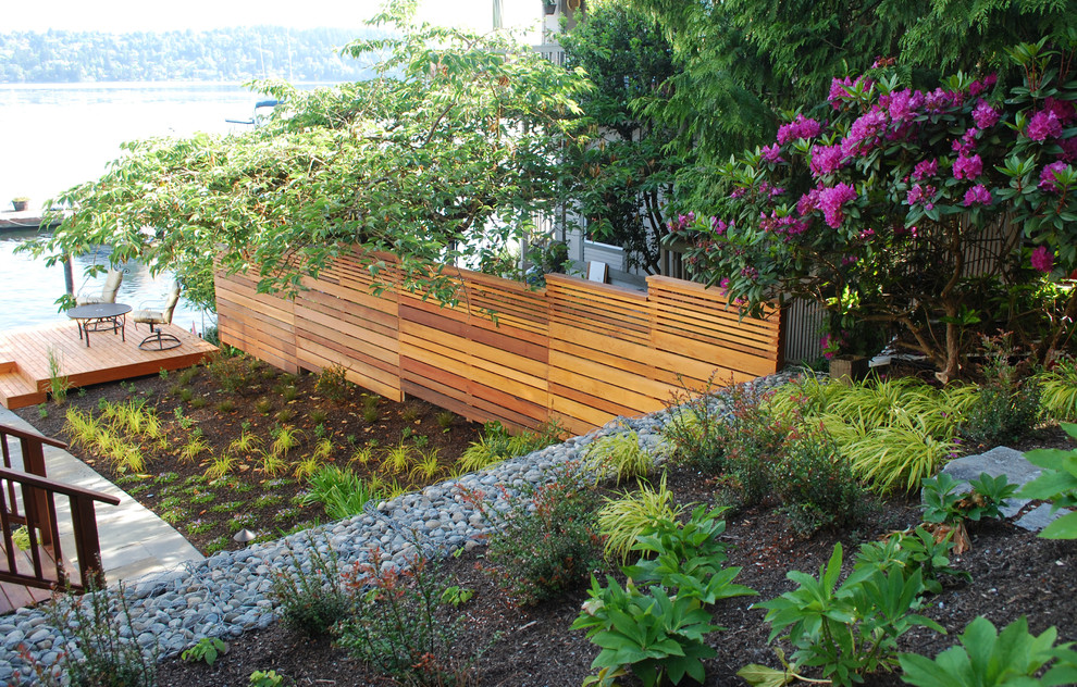 Design ideas for a small modern sloped partial sun xeriscape in Seattle with a retaining wall and natural stone pavers.