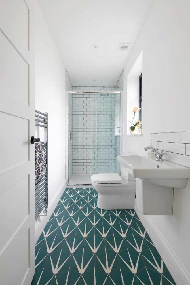 Photo of a small contemporary bathroom in Sussex with an alcove shower, a two-piece toilet, white tile, ceramic tile, white walls, porcelain floors, a wall-mount sink, green floor, a sliding shower screen, an enclosed toilet and a single vanity.