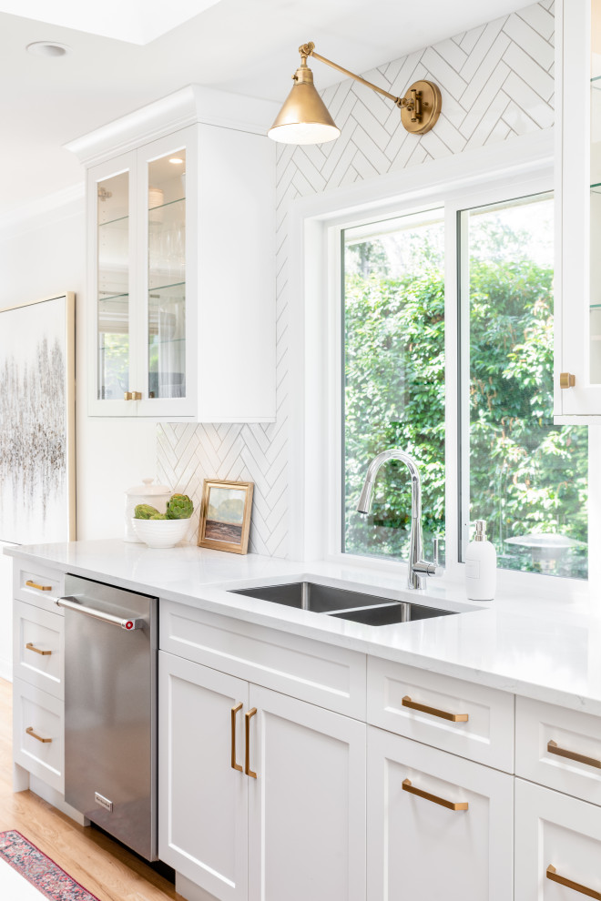 Large transitional l-shaped light wood floor and beige floor open concept kitchen photo in Vancouver with an undermount sink, recessed-panel cabinets, white cabinets, quartz countertops, white backsplash, ceramic backsplash, stainless steel appliances, an island and white countertops