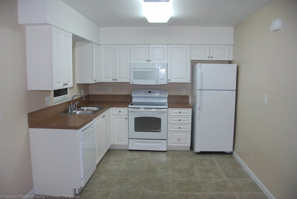 Photo of a small traditional l-shaped eat-in kitchen in Miami with a double-bowl sink, raised-panel cabinets, white cabinets, laminate benchtops, brown splashback, white appliances and ceramic floors.
