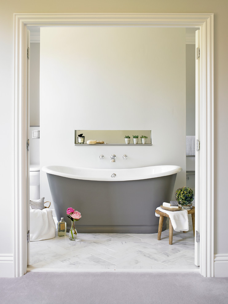 Transitional bathroom in London with a freestanding tub and beige walls.