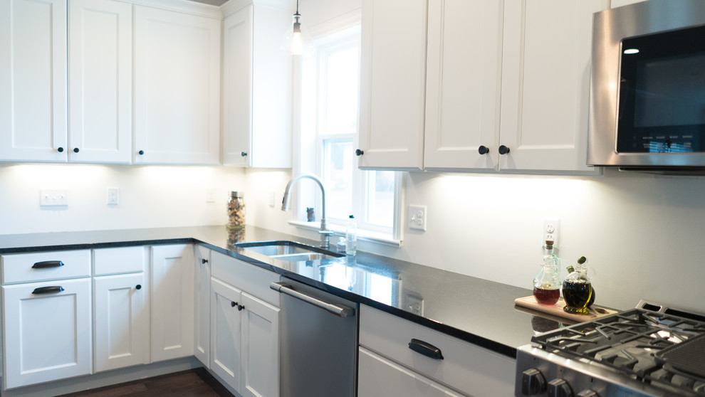Open concept kitchen - mid-sized transitional l-shaped dark wood floor open concept kitchen idea with an undermount sink, shaker cabinets, white cabinets, granite countertops, gray backsplash, stainless steel appliances and an island