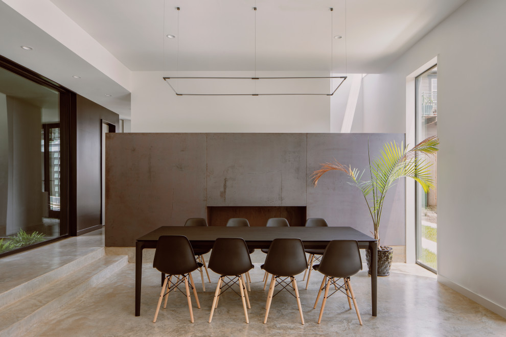 Aménagement d'une salle à manger ouverte sur le salon moderne de taille moyenne avec un mur blanc, sol en béton ciré, une cheminée ribbon, un manteau de cheminée en métal et un sol gris.