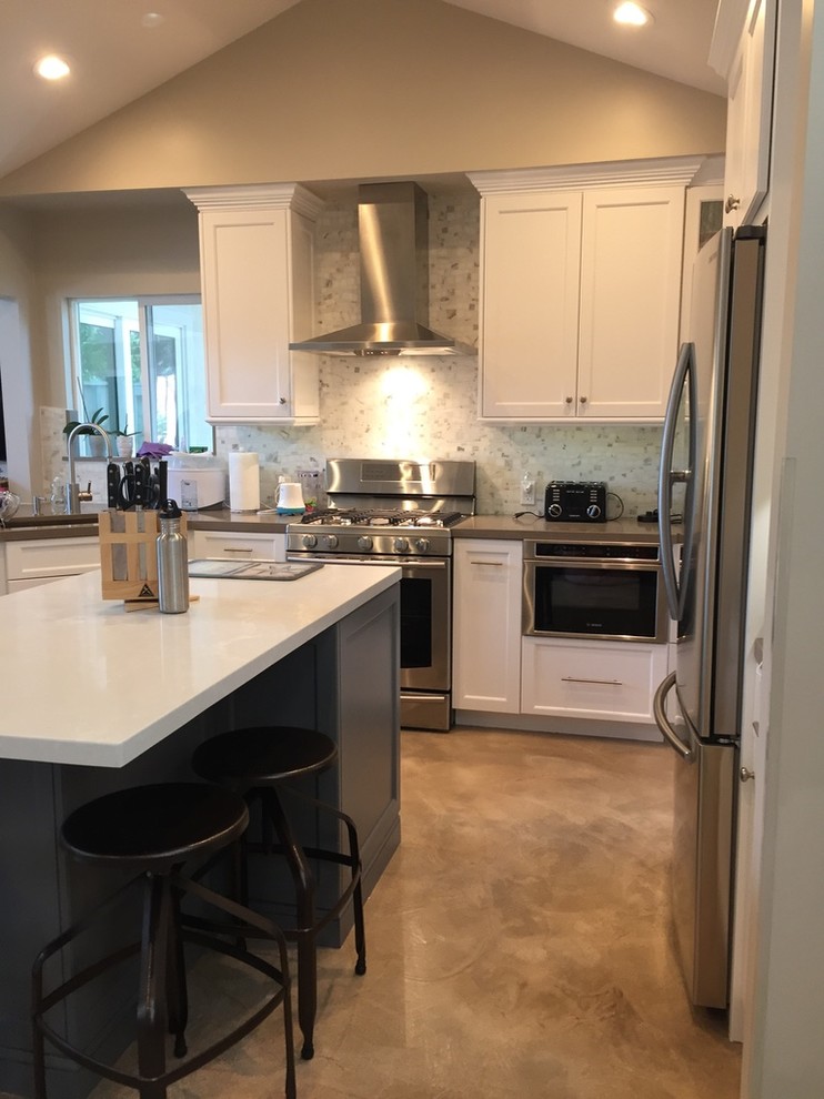 Mid-sized contemporary u-shaped eat-in kitchen in Los Angeles with an undermount sink, shaker cabinets, white cabinets, quartzite benchtops, grey splashback, ceramic splashback, stainless steel appliances, concrete floors and with island.