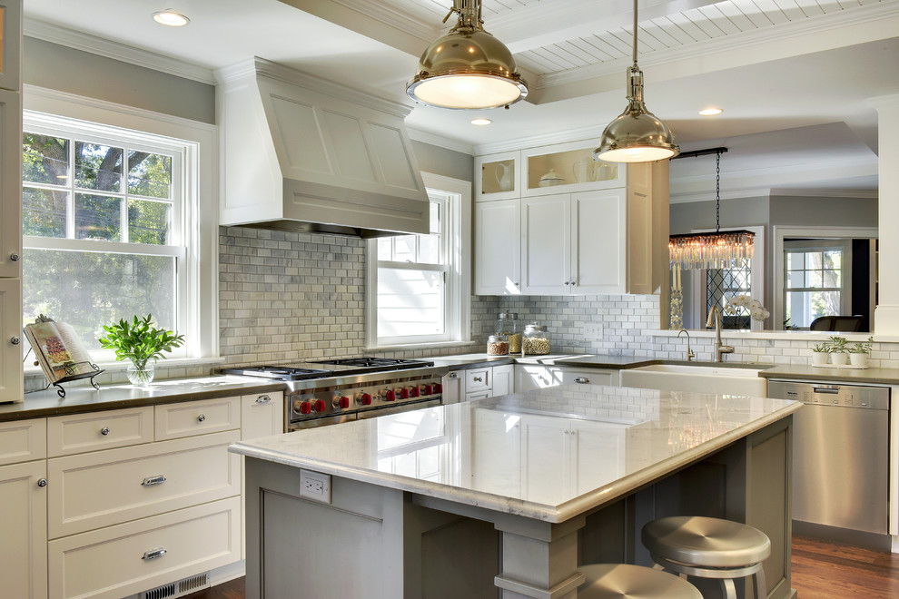 This is an example of a large beach style u-shaped separate kitchen in Phoenix with a farmhouse sink, recessed-panel cabinets, white cabinets, grey splashback, marble splashback, stainless steel appliances, medium hardwood floors, with island, brown floor and grey benchtop.