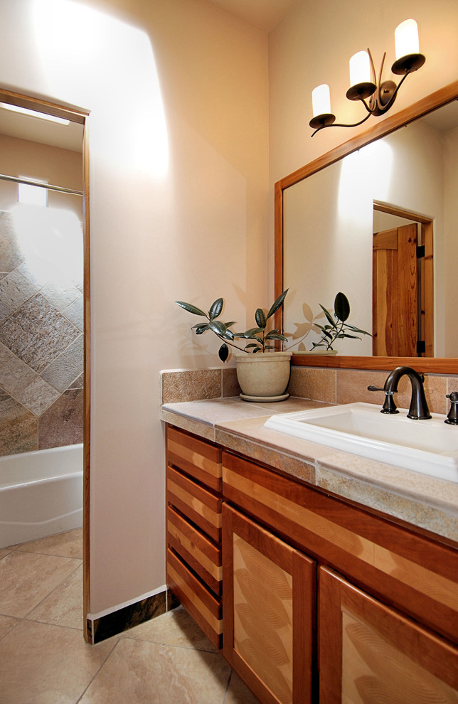 This is an example of a mid-sized asian master bathroom in Portland with recessed-panel cabinets, medium wood cabinets, an alcove tub, a shower/bathtub combo, a one-piece toilet, beige walls, a drop-in sink and a shower curtain.