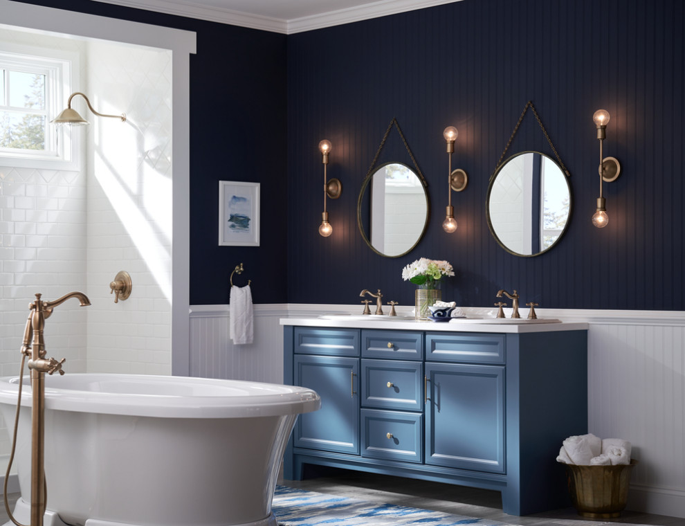 Inspiration for a mid-sized beach style bathroom in Other with recessed-panel cabinets, blue cabinets, a freestanding tub, an open shower, blue walls, light hardwood floors, a drop-in sink, solid surface benchtops, grey floor, an open shower, white benchtops, a double vanity, a freestanding vanity and panelled walls.