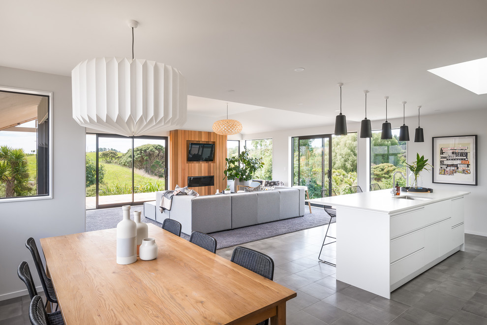 Photo of a modern open plan dining in Wellington with white walls, concrete floors and grey floor.