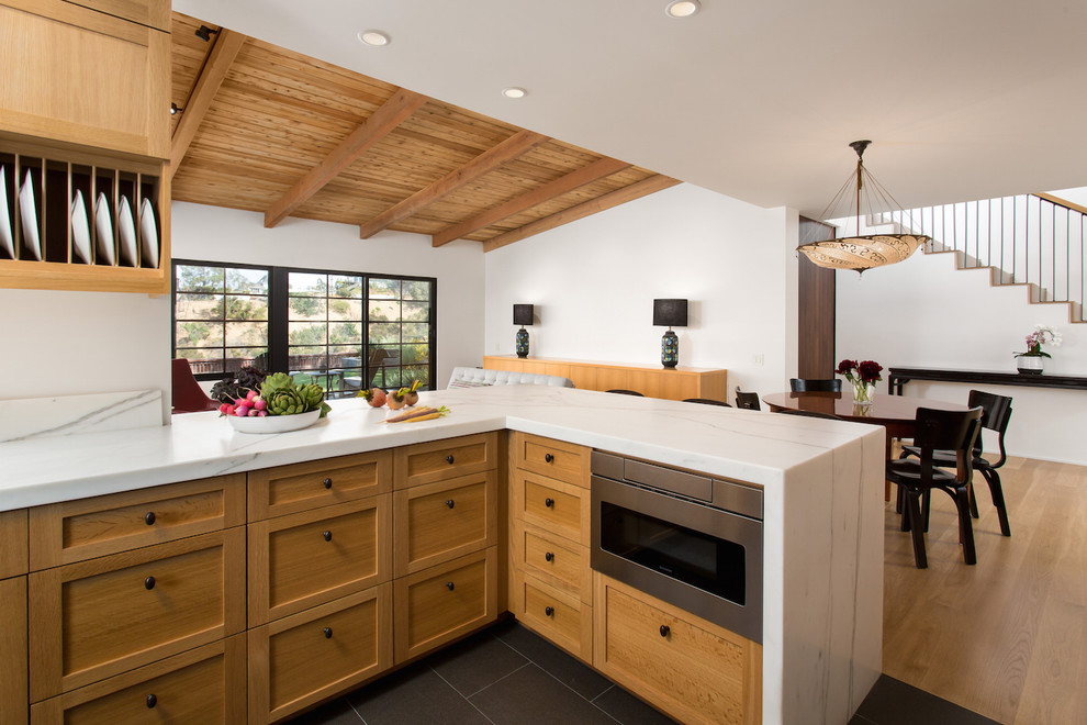 Mid-sized midcentury u-shaped open plan kitchen in Los Angeles with a farmhouse sink, shaker cabinets, light wood cabinets, marble benchtops, white splashback, marble splashback, stainless steel appliances, light hardwood floors, a peninsula and yellow floor.
