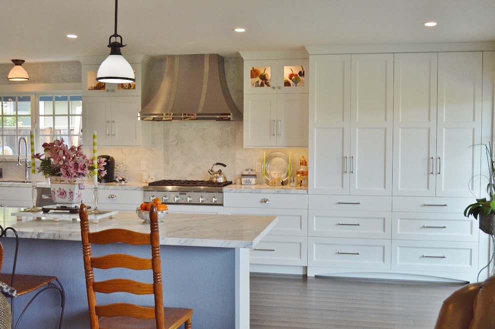 Inredning av ett klassiskt stort kök, med en dubbel diskho, luckor med infälld panel, skåp i rostfritt stål, marmorbänkskiva, vitt stänkskydd, stänkskydd i marmor, rostfria vitvaror, mellanmörkt trägolv och en halv köksö