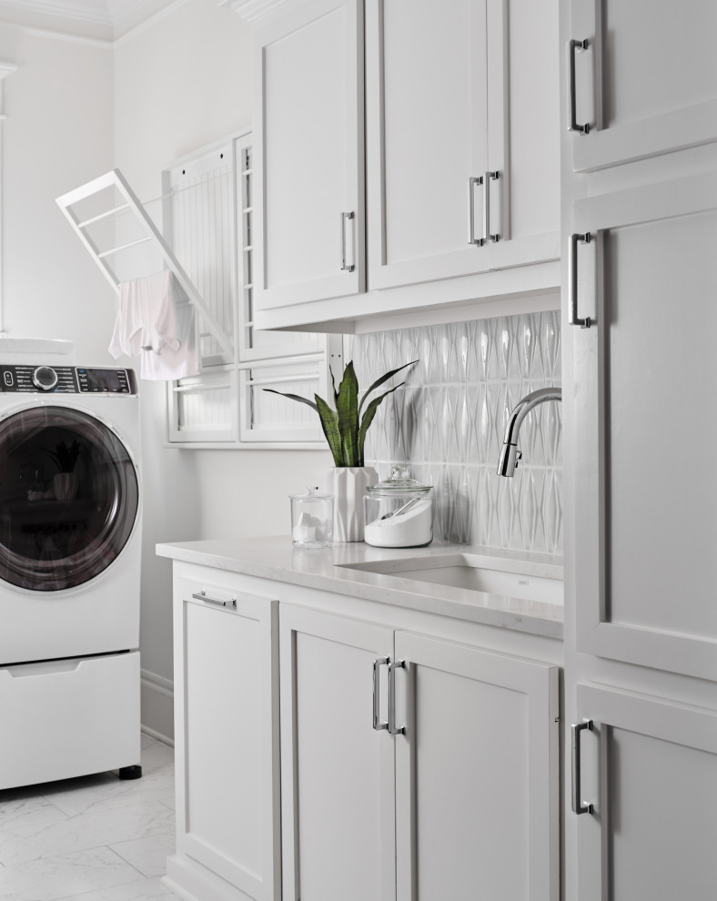 Inspiration for a small beach style l-shaped dedicated laundry room in Houston with an undermount sink, shaker cabinets, white cabinets, quartz benchtops, blue splashback, ceramic splashback, white walls, porcelain floors, a side-by-side washer and dryer, grey floor and white benchtop.