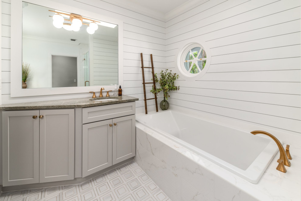 Photo of a mid-sized transitional master bathroom in Miami with shaker cabinets, grey cabinets, a drop-in tub, a corner shower, white tile, porcelain tile, white walls, mosaic tile floors, an undermount sink, granite benchtops, white floor, a hinged shower door, green benchtops, a single vanity, a built-in vanity and planked wall panelling.